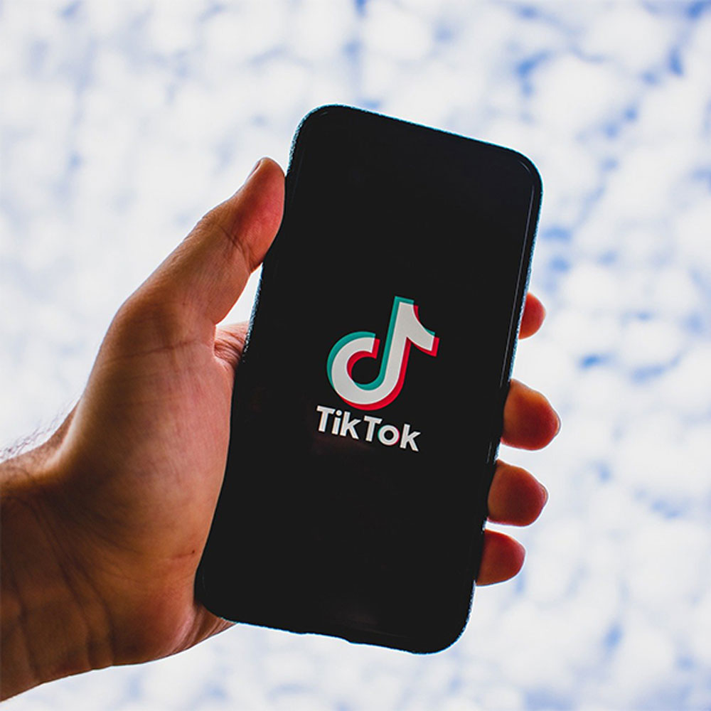 Man holding phone with TikTok logo on the screen