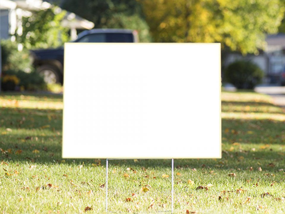 A blank yard sign posted on a lawn.